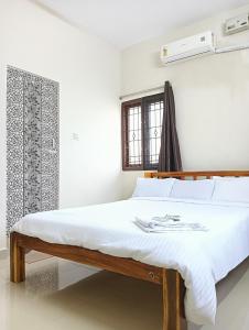 a white bedroom with a bed with white sheets at Rose Villa Pondicherry in Puducherry