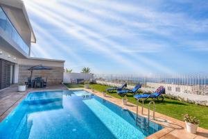 a swimming pool with chairs and an umbrella in a yard at Anya Taghazout - Luxury villa - Pool - 8 ou 9 Px in Taghazout