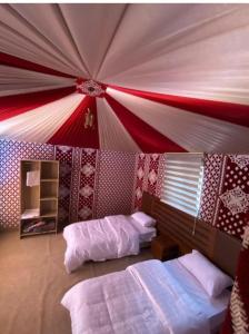 a bedroom with two beds and a red and white ceiling at Desert Life Camp in Wadi Rum