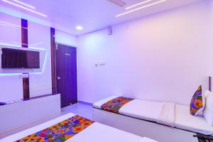 a white room with two beds and a tv at FabHotel Heritage Ruby in Kolkata