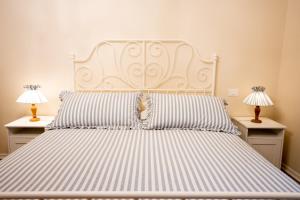uma cama grande com almofadas listradas e 2 candeeiros em Casa vacanze Dentro le Mura em Gualdo Tadino