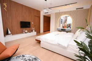 Sandy 1BR Soul Beach Mamsha Al Saadiyat Island في أبوظبي: غرفة نوم بسرير ابيض وتلفزيون بشاشة مسطحة