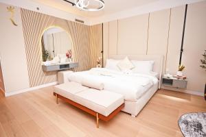 a white bedroom with a white bed and a bench at Sandy 1BR Soul Beach Mamsha Al Saadiyat Island in Abu Dhabi