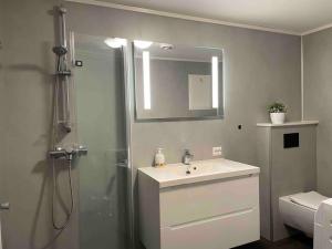 a bathroom with a sink and a shower with a mirror at Moderne leilighet i Alta in Alta