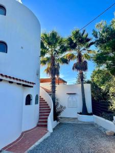 a white house with palm trees and a staircase at apartment with magnificient Es Vedra view in Cala Vadella