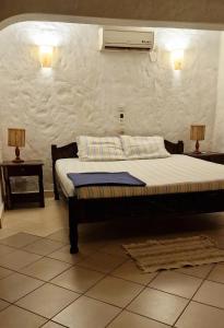 een slaapkamer met een bed met airconditioning aan de muur bij Frangipani Cottages in Diani Beach +44 foto's