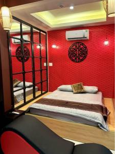 ein Schlafzimmer mit einem Bett mit einer roten Wand in der Unterkunft NHÀ NGHỈ TÚ SỰ in Vĩnh Long