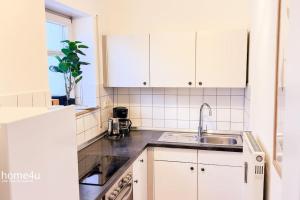 uma cozinha com armários brancos e um lavatório em City-Suite, Zentral / Tiefgarage em Straubing