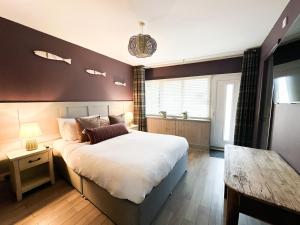 a bedroom with a large bed and a table at Harbour Way Cottage in Seahouses