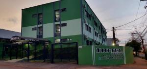 a green building with a sign in front of it at Uniflat Hotel Bauru in Bauru