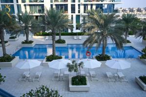 - une vue sur la piscine bordée de parasols et de palmiers dans l'établissement Sandy 1BR Soul Beach Mamsha Al Saadiyat Island, à Abu Dhabi