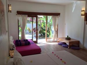 a bedroom with a bed and a table and a window at Rumah Cahaya in Gili Trawangan