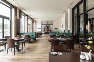 a dining room with tables and chairs and windows at IntercityHotel Dresden in Dresden