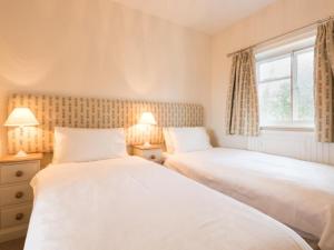 two beds in a bedroom with two lamps and a window at 2 Bed in Bassenthwaite SZ381 in Bassenthwaite Lake
