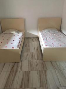 two beds in a room with wooden floors at Villa lake ohrid in Pogradec