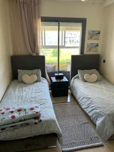1 dormitorio con 2 camas y ventana en Nice appartement Blanca Beach, en Casablanca
