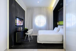 a bedroom with a white bed and a chair at Poli House by AFI Hotels in Tel Aviv