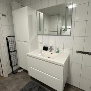 La salle de bains blanche est pourvue d'un lavabo et d'un miroir. dans l'établissement Lofoten Overnatting - Leknes, à Leknes