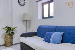 a blue couch in a living room with a clock at Peaceful 1BR maisonette with Sofa Bed with WIFI by 360 Estates in St. Paul's Bay