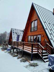 Cabaña de madera con nieve en el suelo y las ventanas en Twin Cabins / Cabanele Gemene, en Suceava