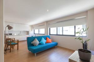a living room with a blue couch and a kitchen at Picaria - Orange in Porto +10 photos
