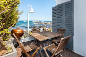 a patio with a table and chairs and the ocean at Sea Haven - Bakoven Beach Front Villa in Cape Town