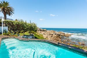 a swimming pool with the ocean in the background at Sea Haven - Bakoven Beach Front Villa in Cape Town