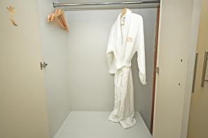 una giacca bianca appesa a un attaccapanni in un armadio di 3BR Grand Residence Corniche Allure a Abu Dhabi Altre 46 foto