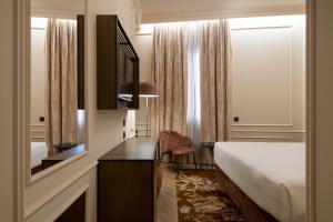 een hotelkamer met een bed, een bureau en een spiegel bij Palazzo Montebello in Florence