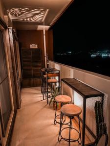 una fila de mesas y taburetes en un balcón por la noche en オーシャンテラス瀬底 Room403 en Motobu