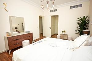 a white bedroom with a large bed and a mirror at Beach bliss 3BR apartment Corniche in Abu Dhabi