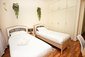 two beds in a room with white walls and wooden floors at Beach bliss 3BR apartment Corniche in Abu Dhabi