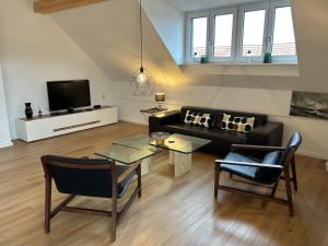 a living room with a couch and a tv at Wohnen auf Zeit - Dachgeschosswohnung mit Bergblick in Bruckmühl