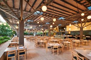 an empty restaurant with tables and chairs and lights at Pine Beach Pakostane - All Inclusive light in Pakoštane