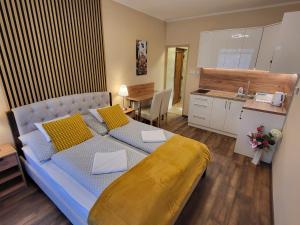 a bedroom with a large bed and a kitchen at Glória Apartman Szarvas in Szarvas
