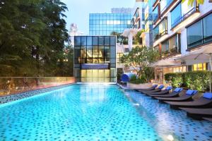a swimming pool with chairs and a building at Park Regis Singapore in Singapore