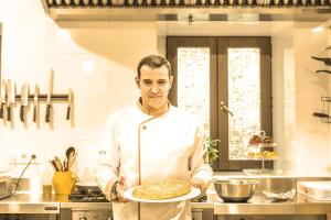 a man in a kitchen holding a pizza on a plate at Teatrisso Hotel Palacio in Cuzcurrita-R&iacute;o Tir&oacute;n