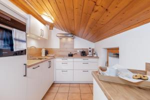 una cucina con armadi bianchi e soffitto in legno di Ferienwohnungen Marietta a Reit im Winkl