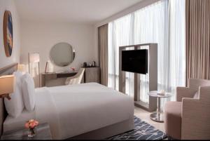 een witte hotelkamer met een groot bed en een televisie bij Hanza Tower Hotel 5 Stars in Szczecin
