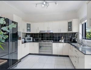 una gran cocina blanca con armarios y electrodomésticos blancos en Book this Cozy Haven Room for your next stay Shared Facilities, en Guildford
