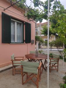 een patio met een houten tafel en stoelen bij Το σπίτι με τις βουκαμβίλιες in Ayia Evfimia