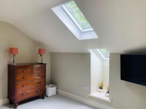 a bedroom with a skylight and a tv and a dresser at Luxury rural retreat near Rutland water in Greetham