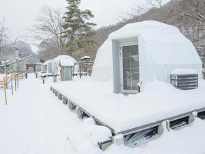 une maison igloo recouverte de neige dans une cour dans l'établissement Ryokan HANAEMI, à Otaru