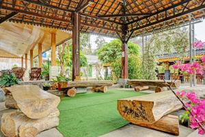 a pavilion with wooden benches and a green floor with flowers at Capital O 93345 The Saka Guest House Syariah in Bandar Lampung