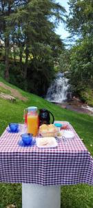 stół piknikowy z jedzeniem i sokiem oraz wodospad w obiekcie Chalé Lírio Cachoeira do Vale w mieście Monte Verde