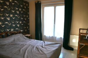 Schlafzimmer mit einem Bett vor einem Fenster in der Unterkunft La maison dans le pré in Agon Coutainville