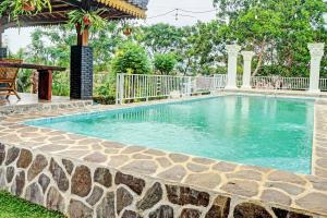 a swimming pool in a yard with a stone wall at Capital O 93345 The Saka Guest House Syariah in Bandar Lampung