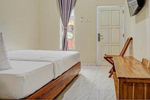 a bedroom with a bed and a desk and a window at Capital O 93345 The Saka Guest House Syariah in Bandar Lampung