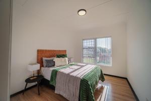 a white bedroom with a bed and a window at Leadwood House in Jeffreys Bay