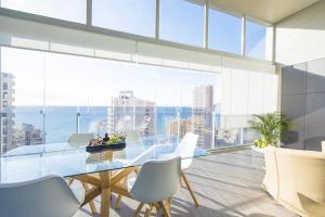 a dining room with a glass table and white chairs at Apartamento Natsu - PlusHolidays in Calpe